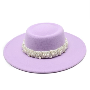 Detail of lavender wide-brim boater hat featuring elegant white pearl ribbon decoration