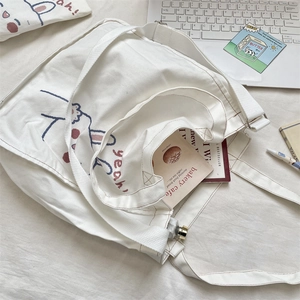 Detalle del bolso tote de lona blanca con lindo estampado de conejo y correas ajustables