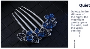 Close-up of four-tooth silver hair comb featuring blue teardrop crystals and navy rhinestones