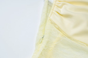 Detailed macro view of the invisible zipper and lace stitching on the cream-colored dress
