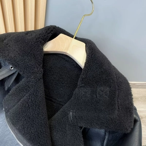 Detailaufnahme einer schwarzen Lammfelljacke mit weicher Textur und Kunstleder-Oberfläche