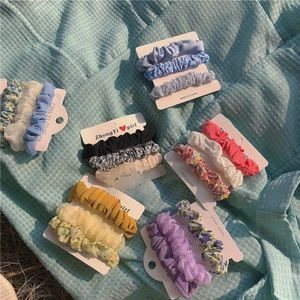 Set of 3 floral scrunchies in chiffon and mesh fabric on a textured blue background