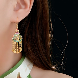 Détail macro de boucles d'oreilles cœur triangle en or 18 carats avec émail et pompons longs