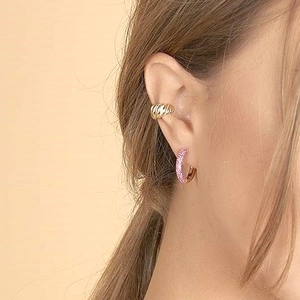 Detail of twisted gold ear cuff and pink zircon hoop earring worn on female ear