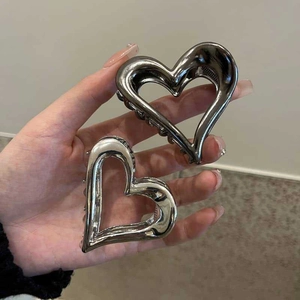 Detailed view of large heart-shaped metal hair claws in glossy silver and gunmetal gray