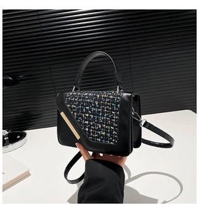 Détails du motif en tweed et barre métallique dorée sur un sac à main noir élégant