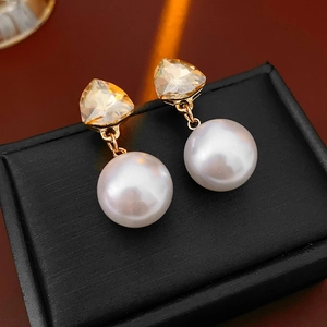 Macro shot of triangle champagne crystal earring with round white pearl drop detail