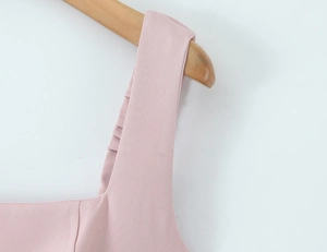 Detailed macro view of pink dress shoulder strap on wood hanger showing woven texture