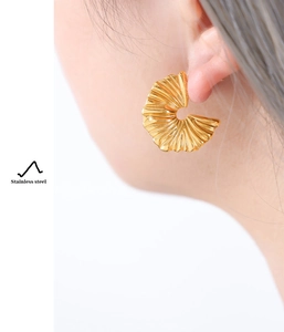 Detailed close-up of pleated fan-shaped 18k gold plated stainless steel earring on model