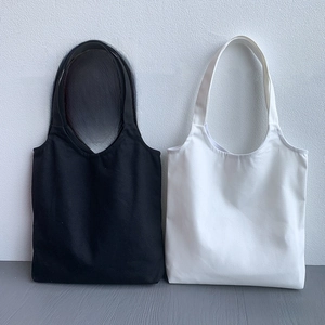 Detail view of black and white plain canvas tote bags with reinforced shoulder straps