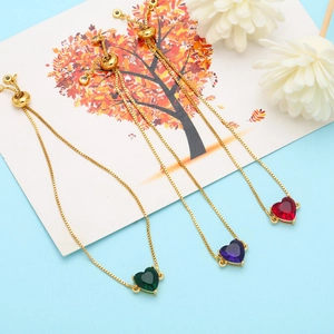 Dettaglio di bracciali con zirconi a cuore in rosso, viola e verde con catene dorate