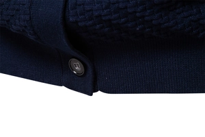 Close-up of navy blue knit fabric texture and black button detail on V-neck cardigan
