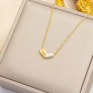 Gros plan d'un collier cœur avec plaquage en or et incrustation de nacre blanche