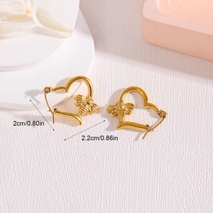 Golden heart earrings with bee accent and size dimensions on a textured surface
