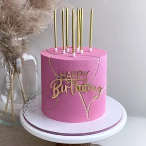 Pink matte birthday cake with gold happy birthday topper and elegant gold candles