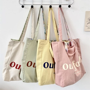 Detail view of four colorful floral canvas tote bags hanging on wall hooks in pastel tones