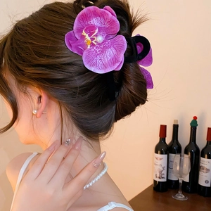 Detail of purple orchid hair claw with white pearl worn on a model hairstyle