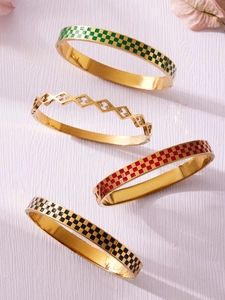 Detailed view of four golden bangles with checkered enamel patterns and zircons
