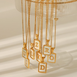 Close-up of 18K gold plated stainless steel initial necklaces with white shell inlay
