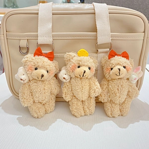 Schattige beige pluchen beer sleutelhangers met roze blos en rode strikken op een tas