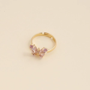Détail d'une bague papillon dorée avec zircon violet et anneau ajustable au design ouvert