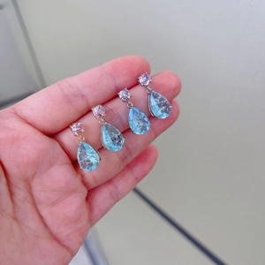 Detail of hand holding light blue teardrop crystal earrings with pink beads