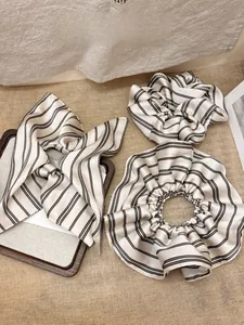 Detail of cream satin scrunchies and headband with elegant black striped pattern