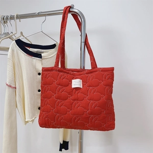 Detail of red quilted tote bag with cute white rabbit embroidery and woven label
