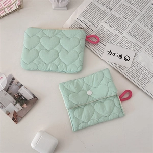 Detailed view of mint green quilted heart pattern storage bags on a lifestyle desk setup