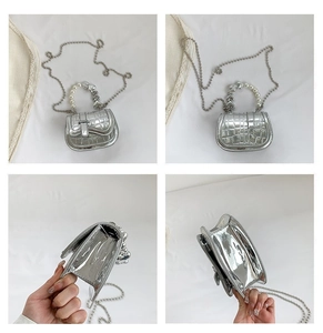 Detail der silbernen Mini-Tasche mit Krokoprägung, Perlenherz-Griff und Kettengurt