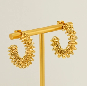 Macro view of gold spiral wire wrapped C-shaped earrings on a T-bar jewelry display