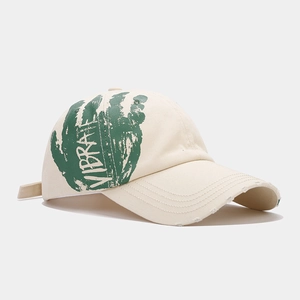 Detail showing green palm print with VIBRATE text and distressed brim on beige cap