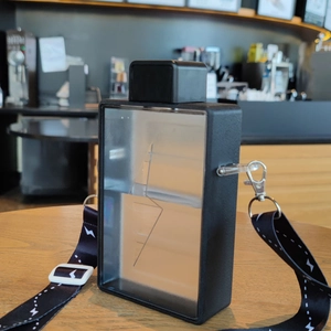 Detail of a book-shaped rectangle plastic water bottle with lightning relief and black strap