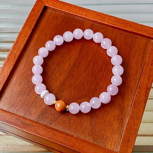 Detail of pink kunzite beaded bracelet with golden accent on a wooden display box