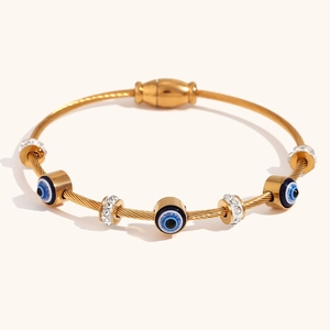 Detail of gold cable bracelet with evil eye charms and sparkling rhinestones