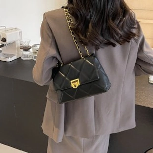 Elegant black quilted chain bag with gold hardware shown on model in a cafe setting
