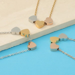 Close-up of triple heart pendants in silver, gold, and rose gold on a stone texture
