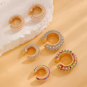 Gold-plated C-shaped ear cuffs with pearls and colorful zircons on a stone display