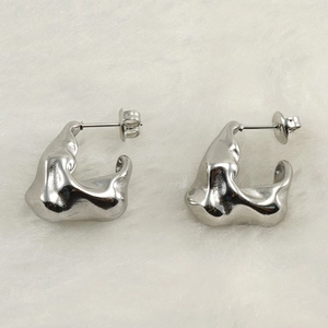 Minimalist irregular lava shaped earrings in silver finish on white textured background