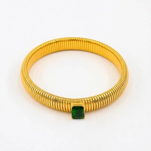 Macro detail of gold-tone Tubogas snake bracelet with emerald green zircon centerpiece