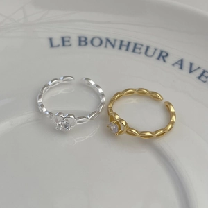 Macro view of gold and silver heart-shaped S925 rings with zircons on a white ceramic plate