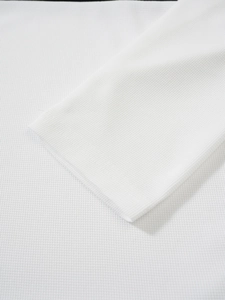 Détail du tissu gaufré blanc et de la couture du poignet sur le polo à manches longues