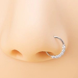 Macro detail of silver nose ring with white zircons on realistic silicone model