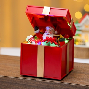 Close-up of a glowing Christmas gift box ornament with Santa and warm LED lighting
