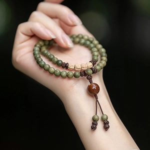 Detailed view of green wood bead bracelet with tassel and ox bone accents on hand