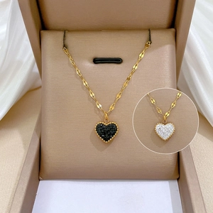 Close-up of heart pendant necklace in gold with micro-inlaid stones and black finish
