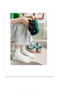Detail of embroidered green NA letter on white, black and green cotton socks
