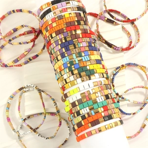 Close-up of bohemian Tila bead bracelets featuring rainbow colors and golden metal spacers