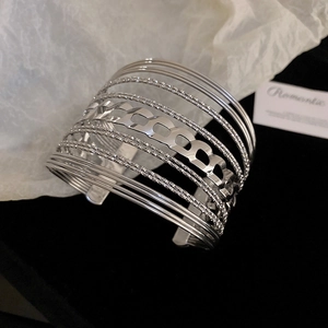 Macro detail of silver layered bangle featuring sand-textured and chain-link hollow patterns
