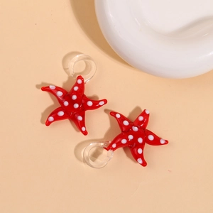 Detail shot of a red 3D glass starfish pendant with white polka dots and a clear loop